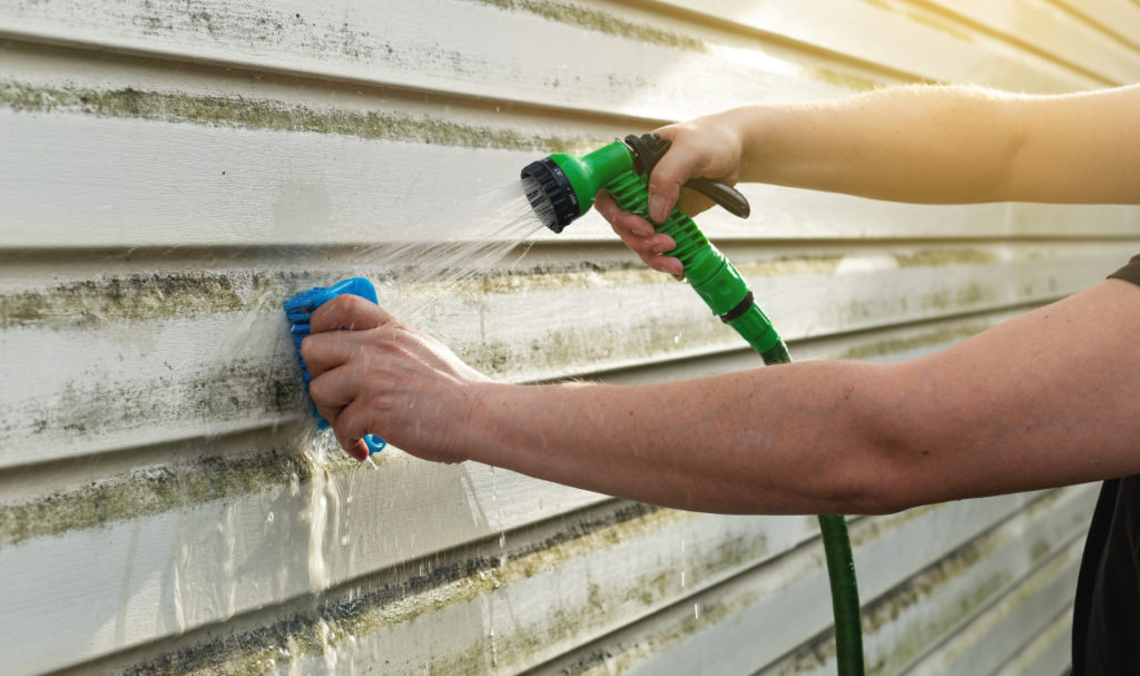 Contractor sealing exterior siding on a Portland home as part of summer maintenance