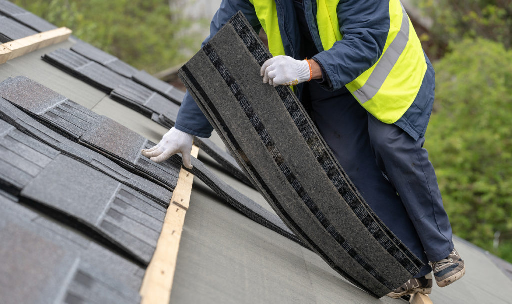 Contractor inspecting roof shingles on a Portland home to check for roof replacement warning signs